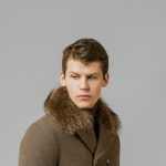 Full length portrait of handsome man in warm coat posing in studio